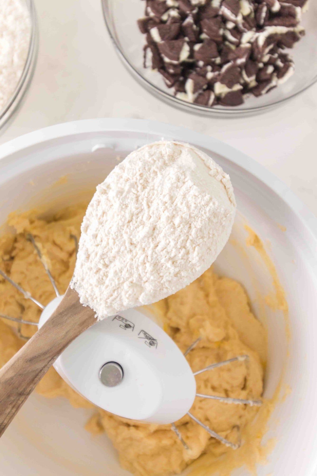 Adding half the flour to the cookie dough. 