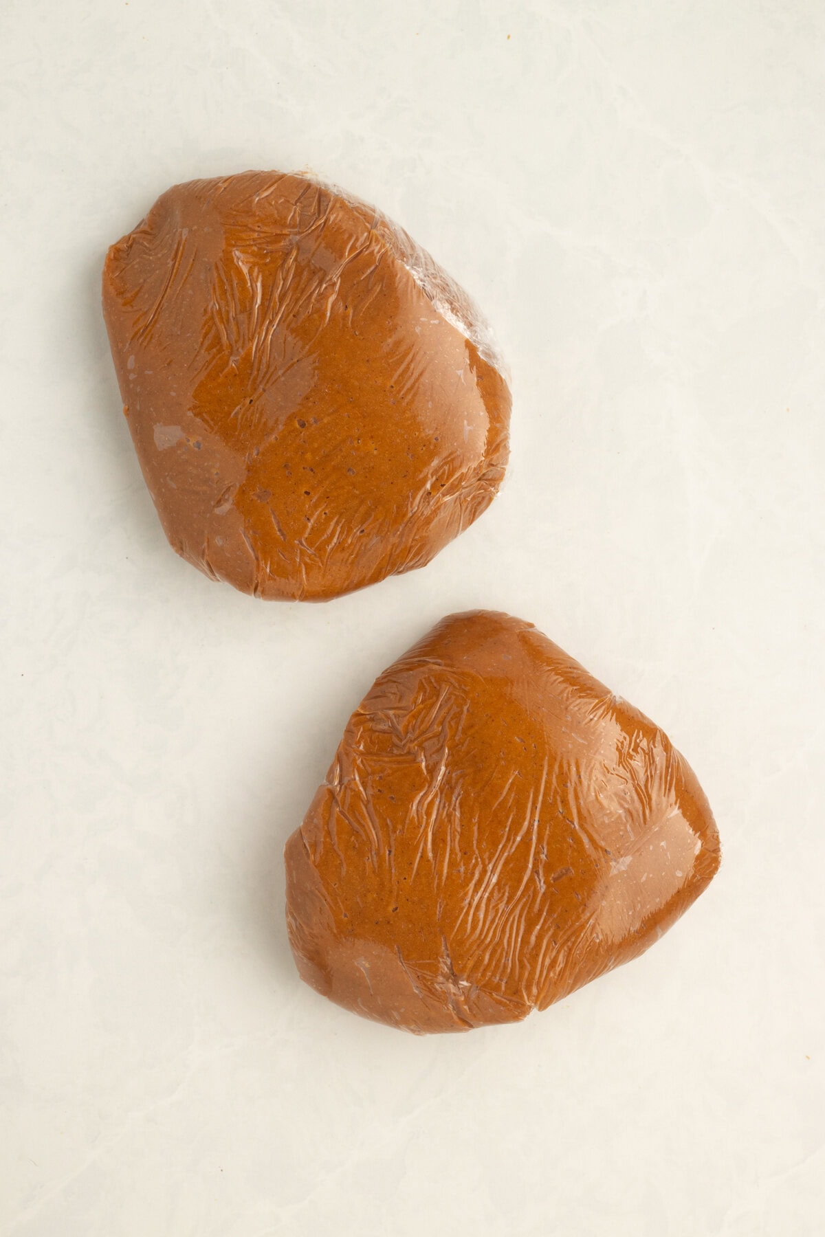 Dough divded into two parts and wrapped in plastic.