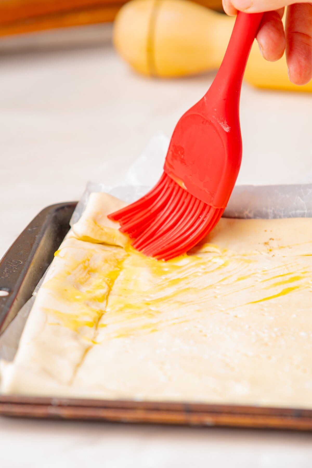 Brushing pastry with egg mixture.