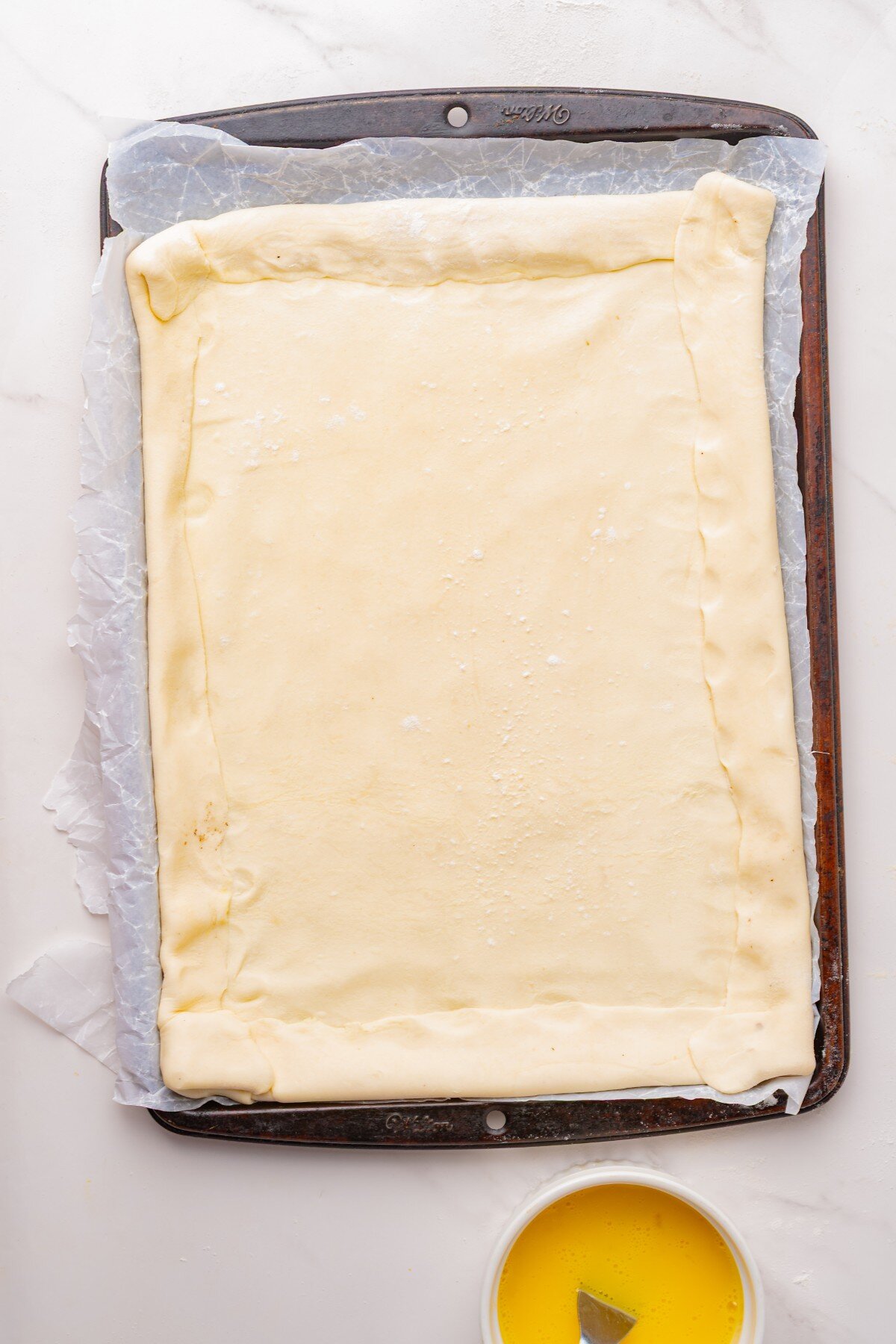 Pastry on parchment on a baking sheet.