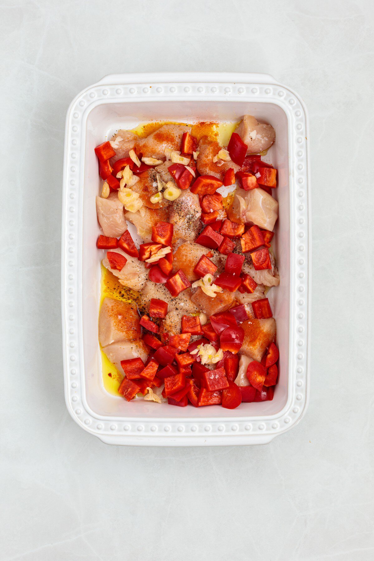 Chicken, red peppers and seasoning in a casserole. 