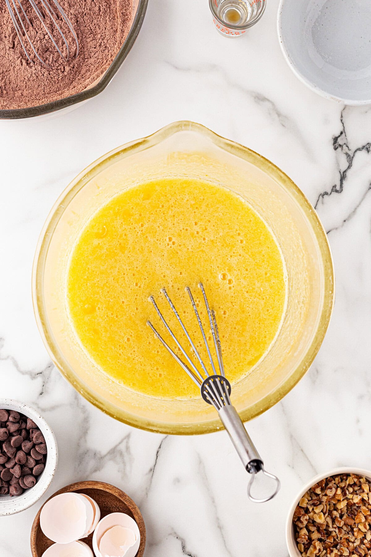 Eggs, vanilla, and sugar whisked in a bowl.