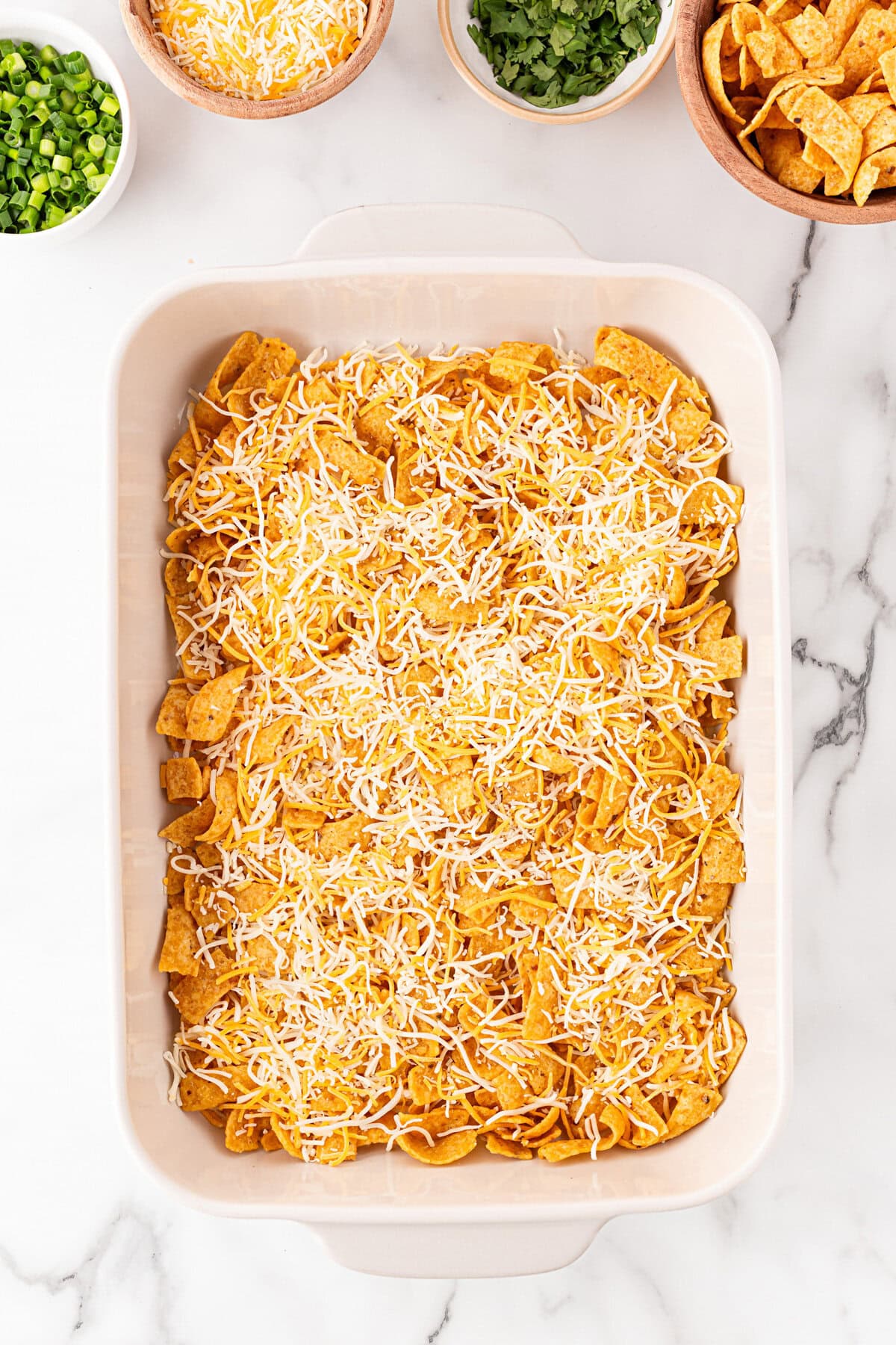 Corn chips and cheese on the bottom of the baking dish.