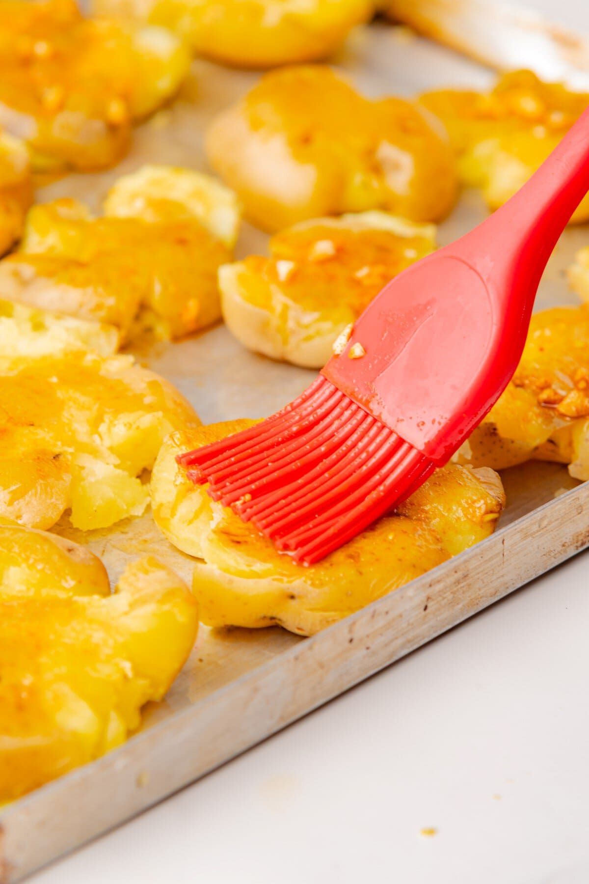 Brushing the oil mixture on the smashed potatoes.