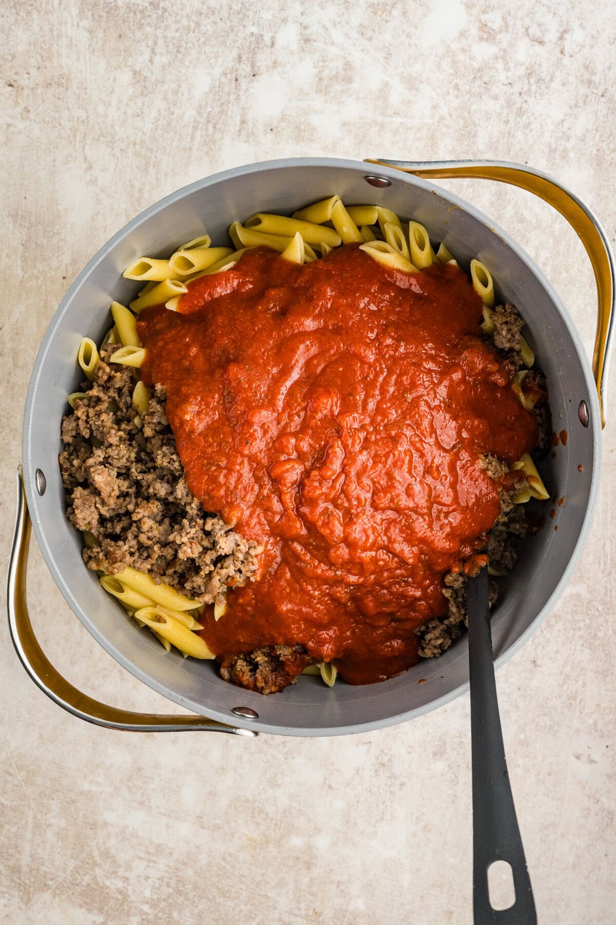 Mixing the pasta, sausage, and sauce together.